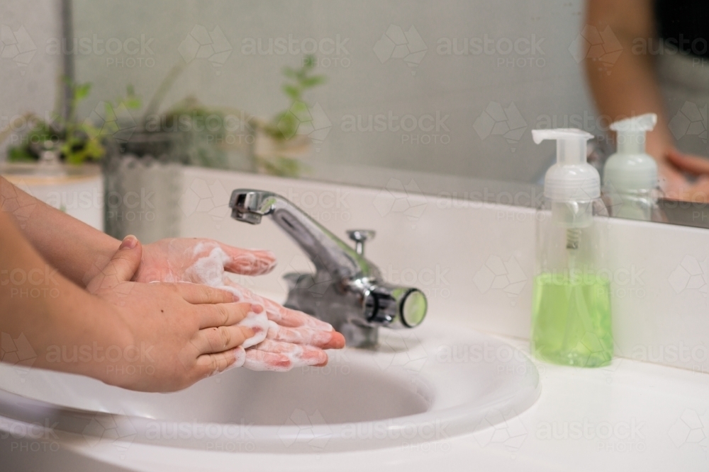 woman washing hands in basin - Australian Stock Image