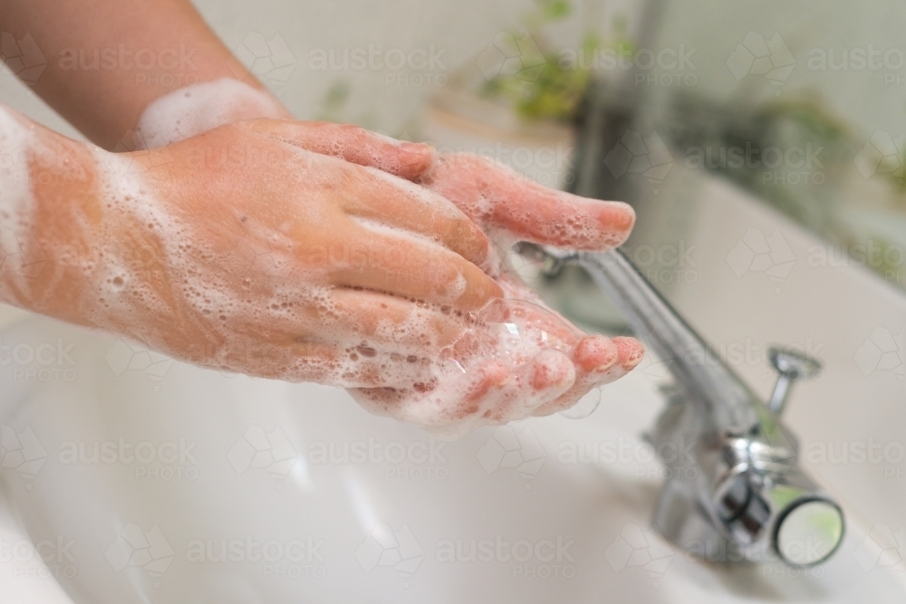 woman washing hands in basin - Australian Stock Image