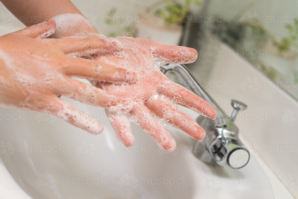 woman washing hands in basin - Australian Stock Image