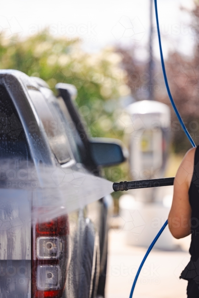 Woman washing vehicle in self-service car wash bay - Australian Stock Image