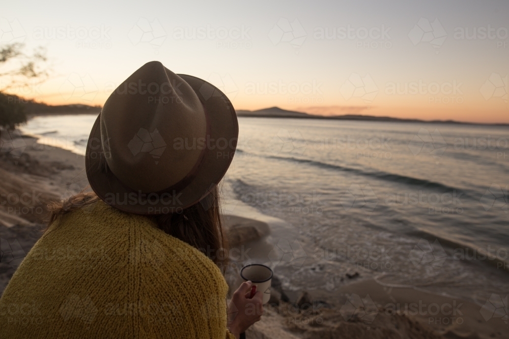Woman watching sunset at beach - Australian Stock Image