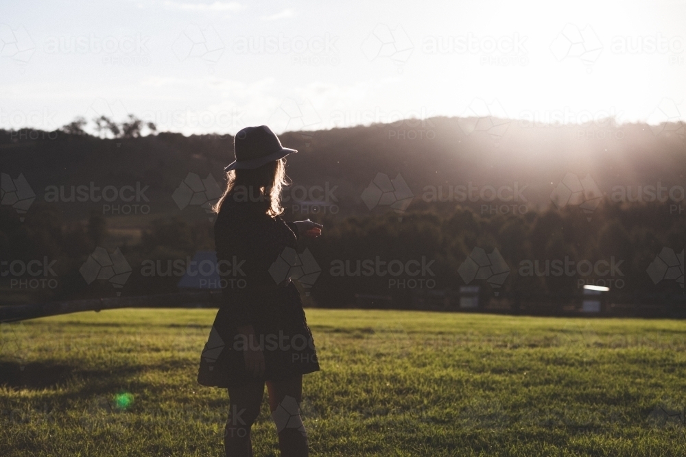 Woman watching the sunset over the hillside in the country - Australian Stock Image