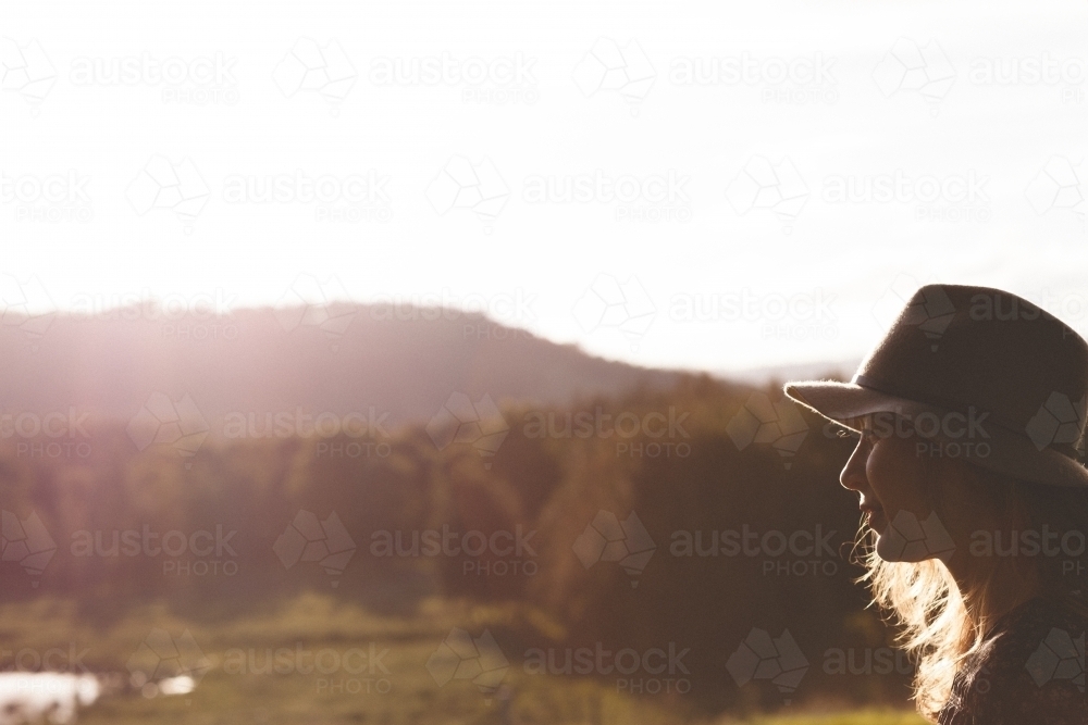 Woman wearing a hat with countryside in the background - Australian Stock Image