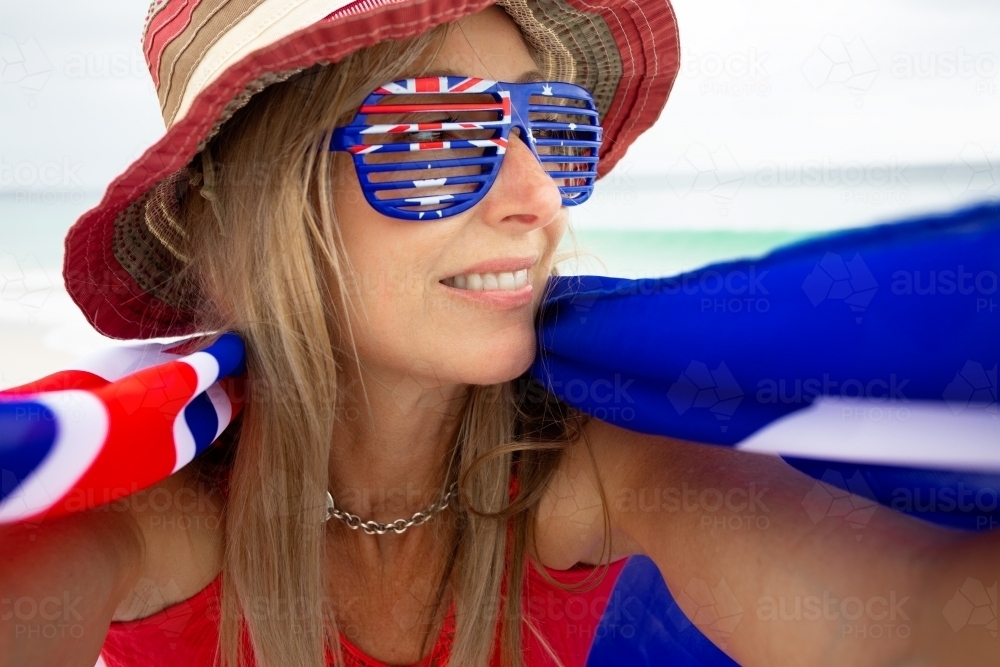Woman wearing Australia flag sunglasses and with flag draped around her shoulders - Australian Stock Image