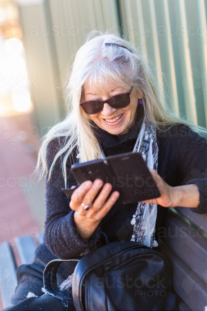 Woman wearing sunglasses looking at smartphone - Australian Stock Image