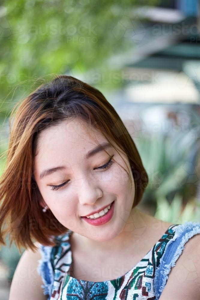 Woman with a smile, looking to the ground - Australian Stock Image