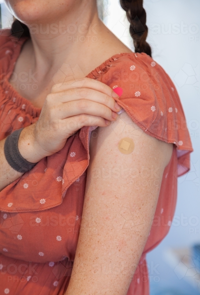 Woman with band aid over Covid-19 vaccine injection site - Australian Stock Image