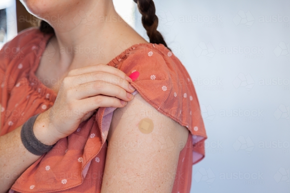 Woman with band aid over Covid-19 vaccine injection site - Australian Stock Image