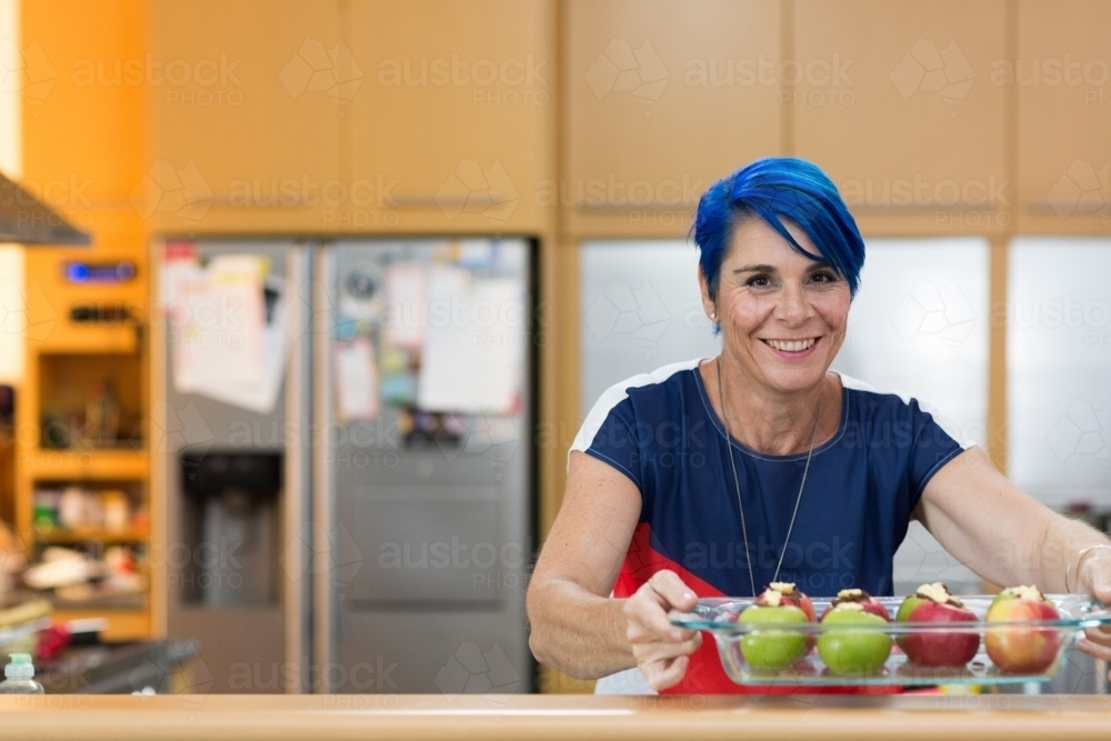 Woman with blue hair preparing apples for baking - Australian Stock Image