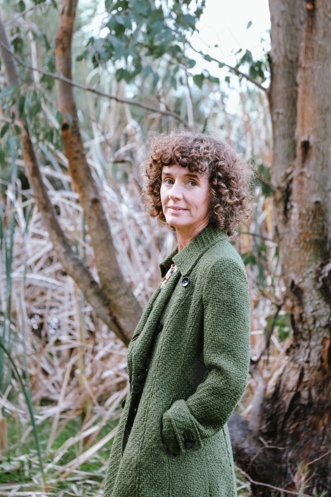 Image of Woman with curly hair posing in front of bushland and reeds ...