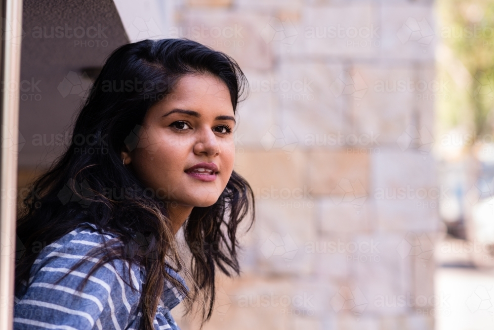 Woman with dark hair wearing stripe shirt looking ahead - Australian Stock Image