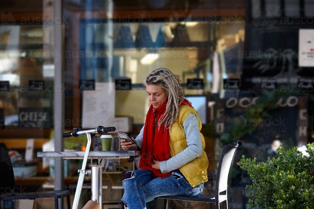 Woman with dreadlocks at cafe with electric scooter - Australian Stock Image
