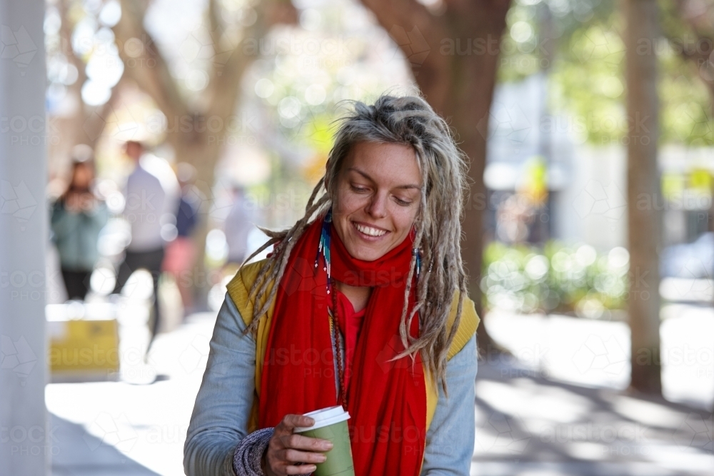 Woman with dreadlocks drinking coffee outdoors at cafe - Australian Stock Image