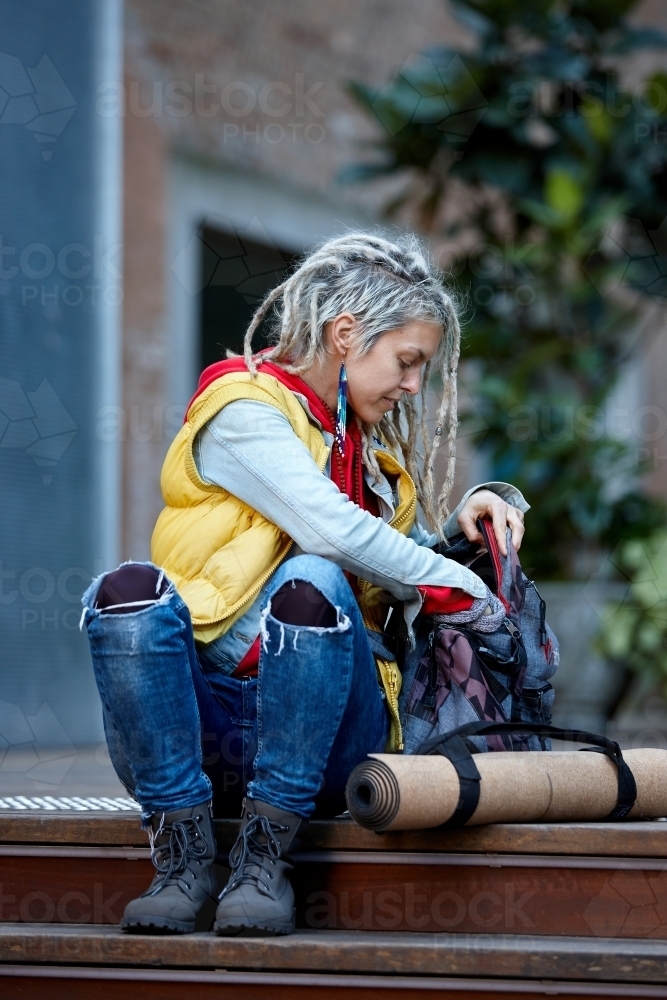 Woman with dreadlocks getting item from backpack - Australian Stock Image