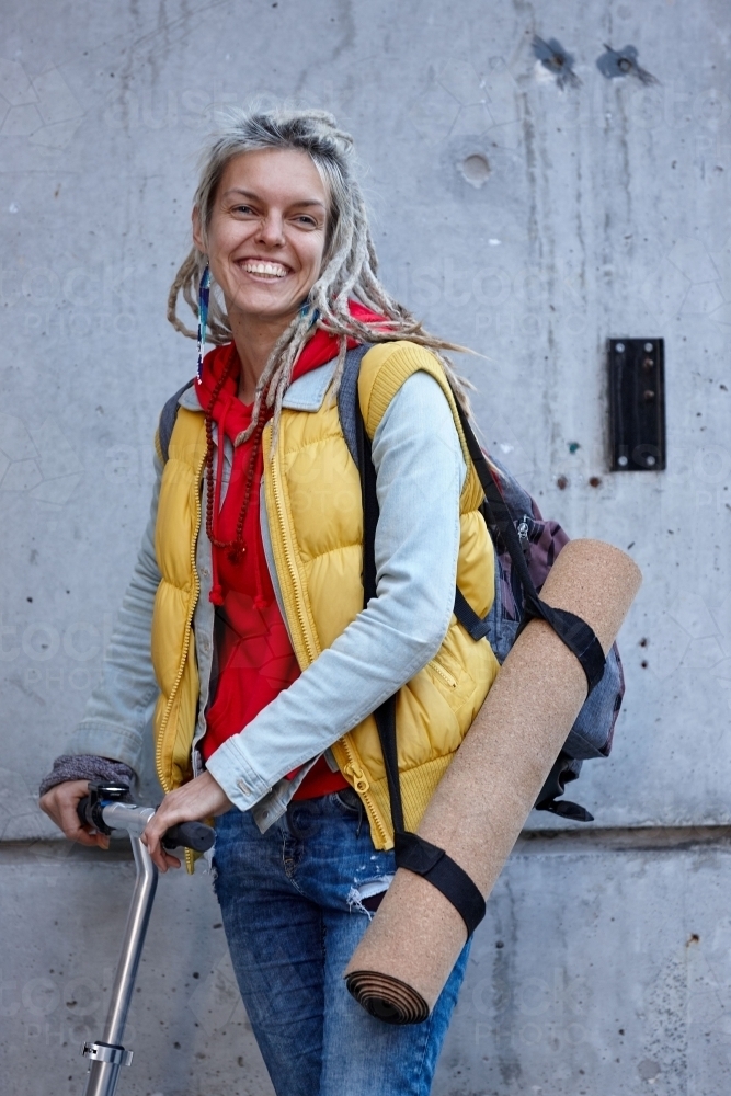Woman with dreadlocks on electric scooter going to her yoga class - Australian Stock Image