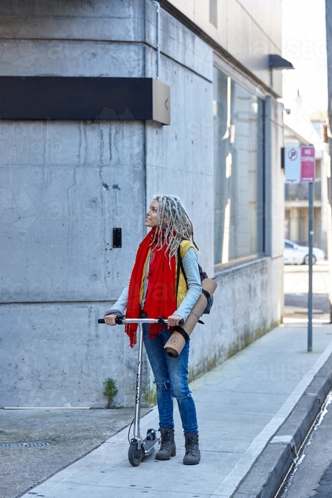 Woman with dreadlocks riding electric scooter - Australian Stock Image