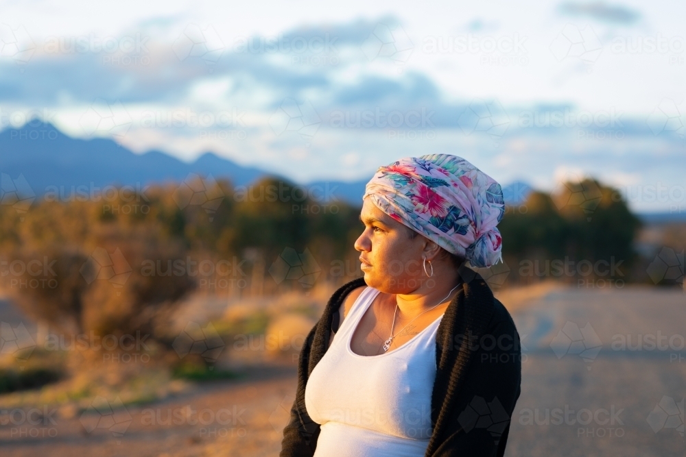 woman  with head wrap looking in to the distance in late afternoon sun - Australian Stock Image