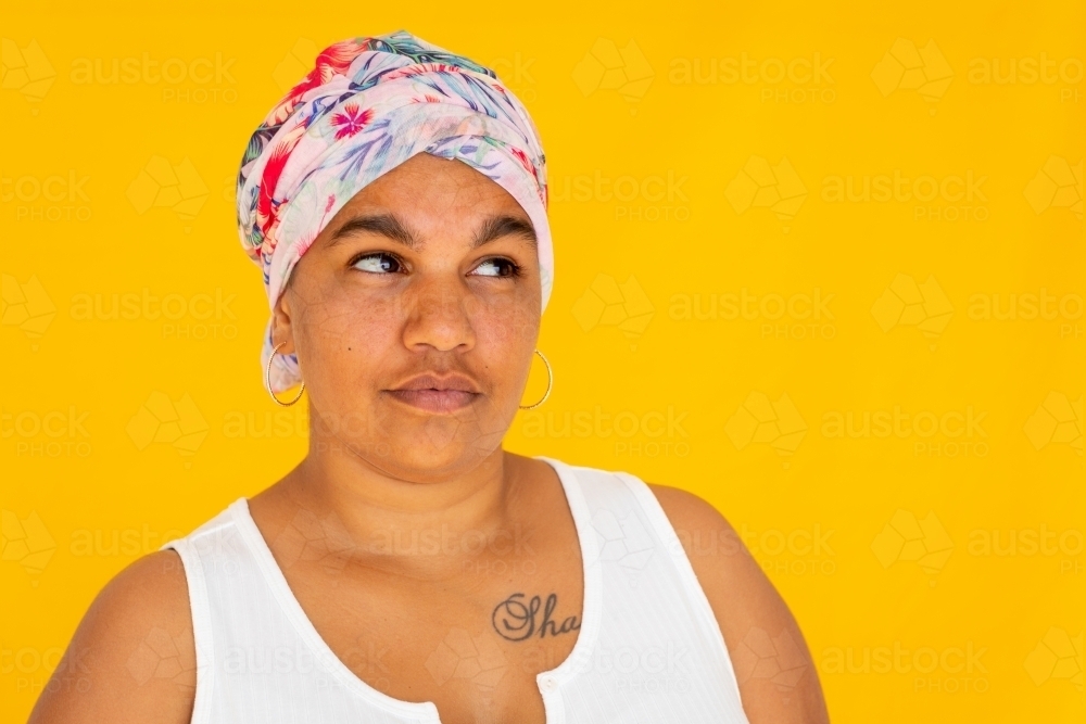 woman with head wrap on bright yellow background - Australian Stock Image