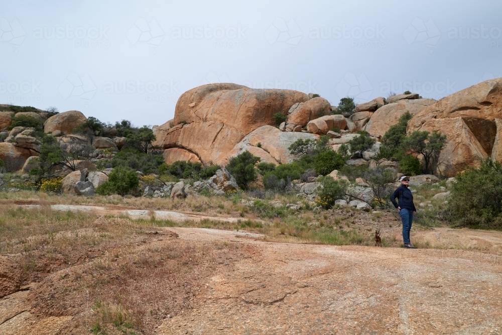 Woman with small dog exploring rugged landscape - Australian Stock Image