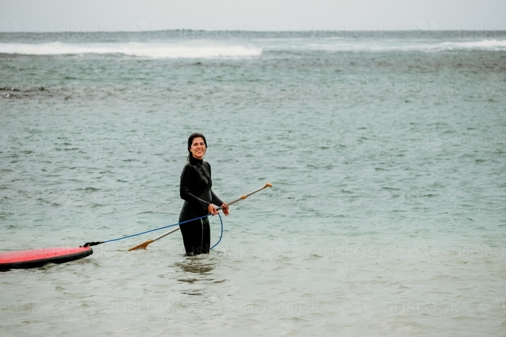 Woman with stand up paddle board in the ocean. - Australian Stock Image