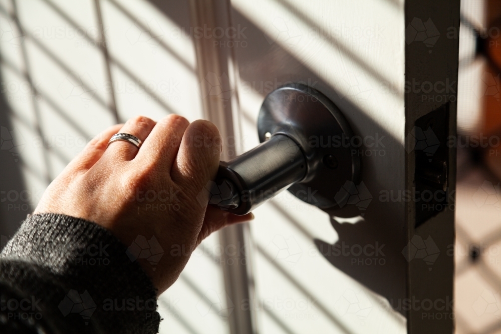 Image of Woman with wedding rings on her finger unlocking front door