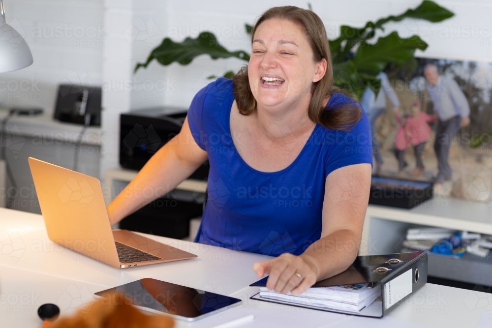 woman working from home with laptop and file on desk - Australian Stock Image