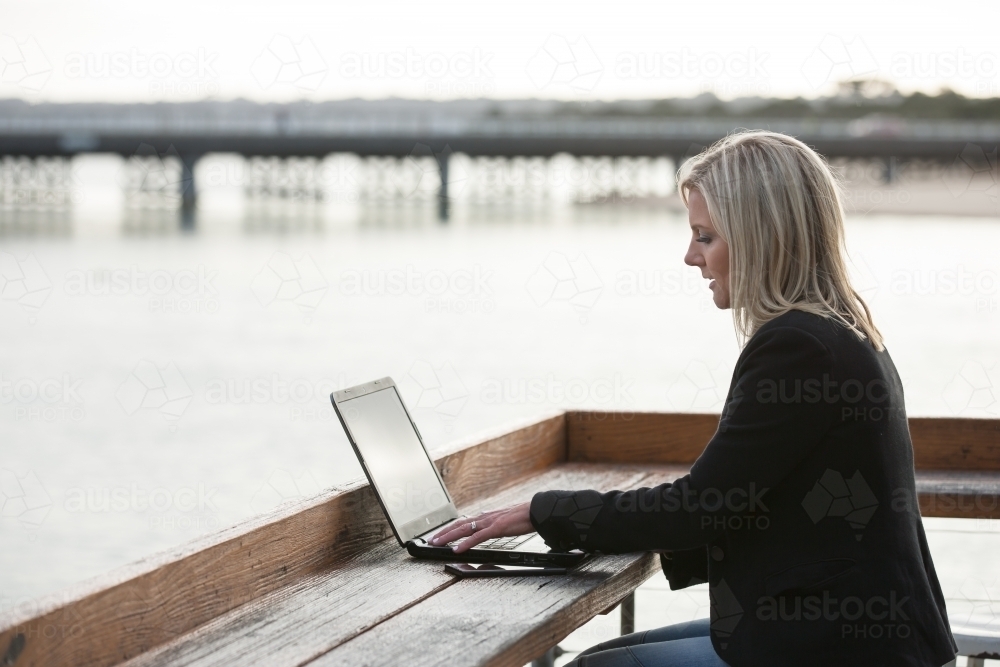 woman working on her laptop at a coastal location - Australian Stock Image