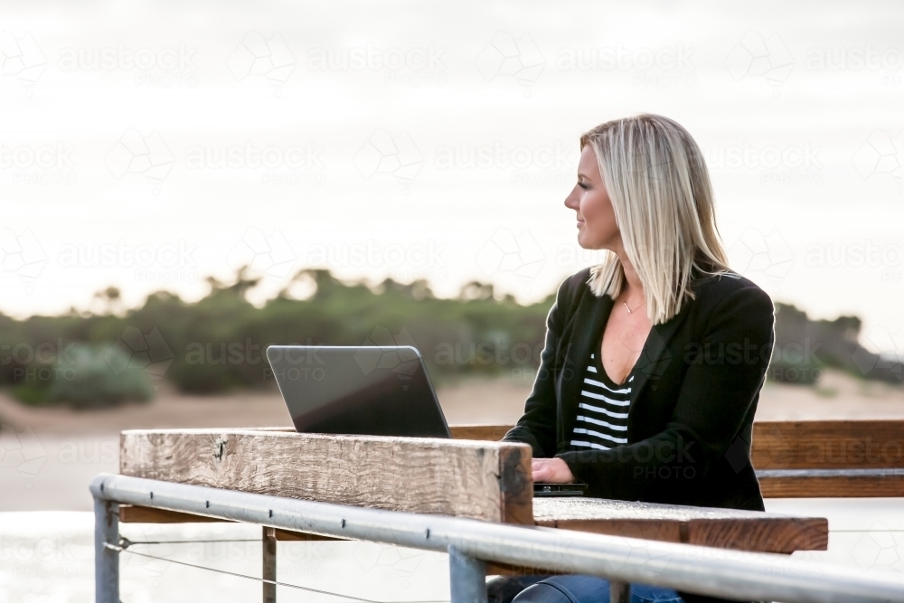 Woman working on her laptop in coastal location - Australian Stock Image