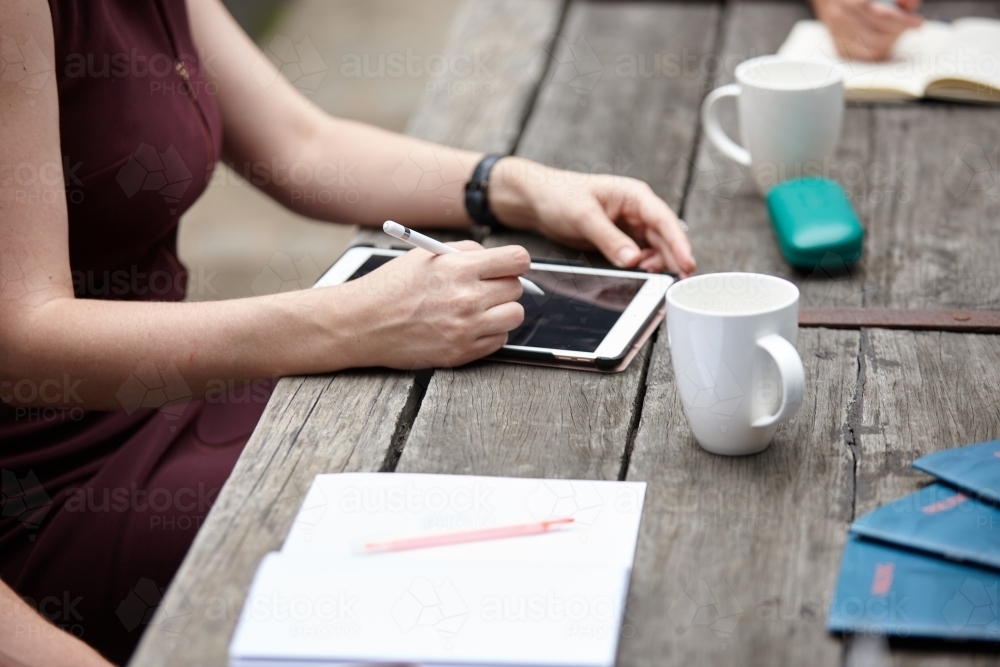 Woman working on touchpad outdoors with colleagues - Australian Stock Image