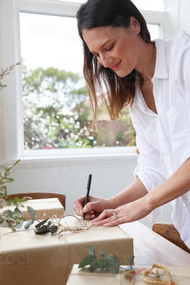 Woman writing gift card/ wrapping presents - Australian Stock Image