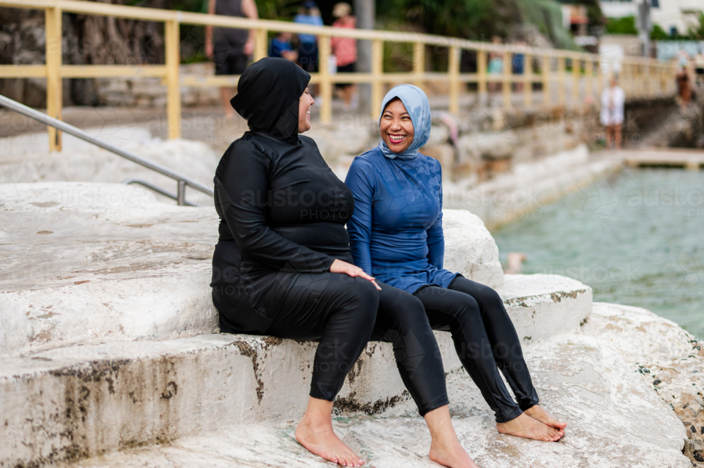 Women in burkinis sitting on the platform of ocean pool - Australian Stock Image