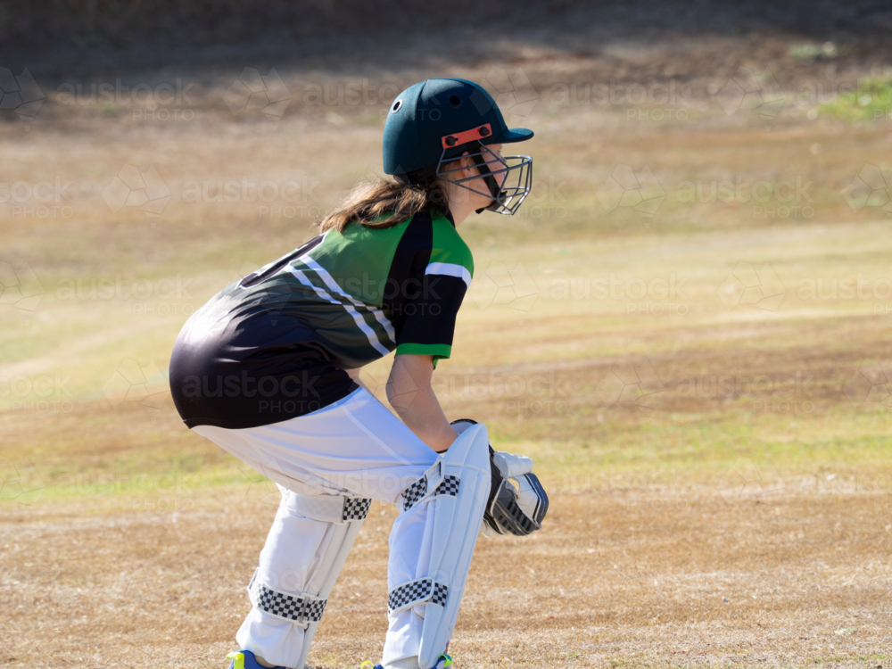 Women's cricket female wicket keeper crouching watching the ball on the field - Australian Stock Image