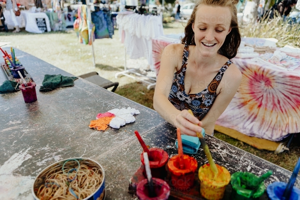 Women sitting at market table doing tie die art - Australian Stock Image