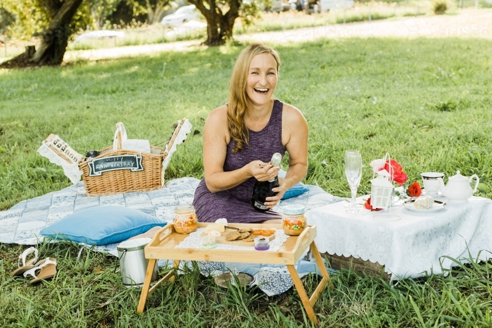 Women sitting at on picnic rug with champagne - Australian Stock Image