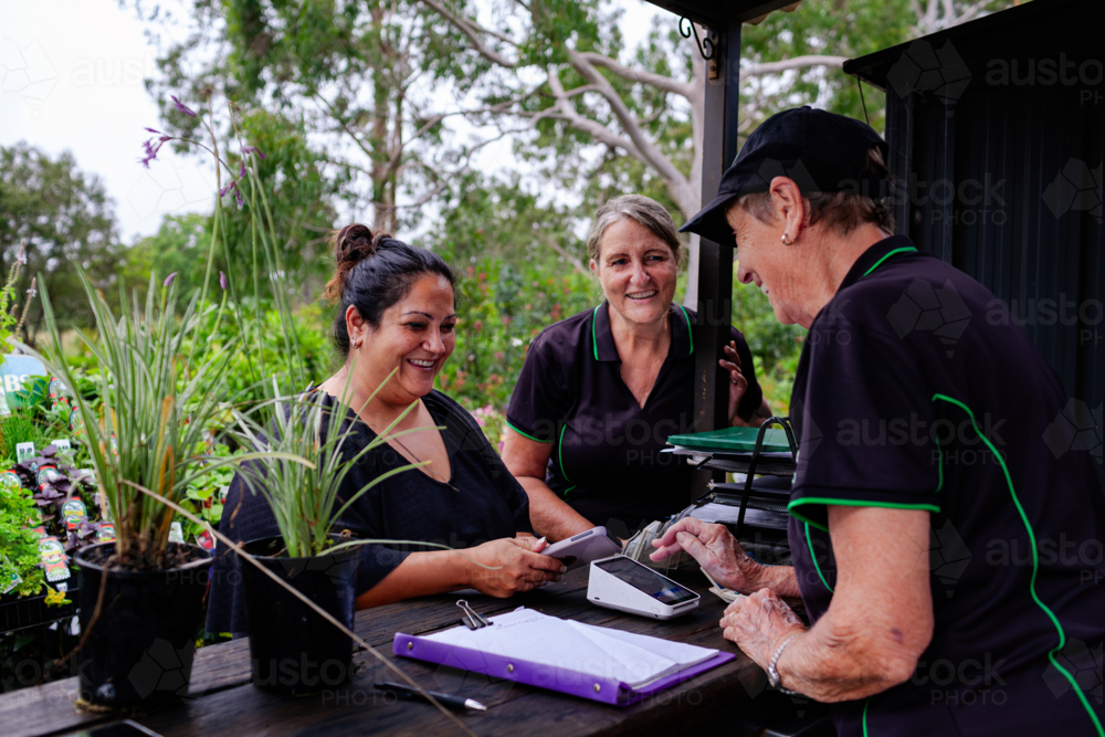 Women together at checkout of small business nursery garden buying plants - Australian Stock Image