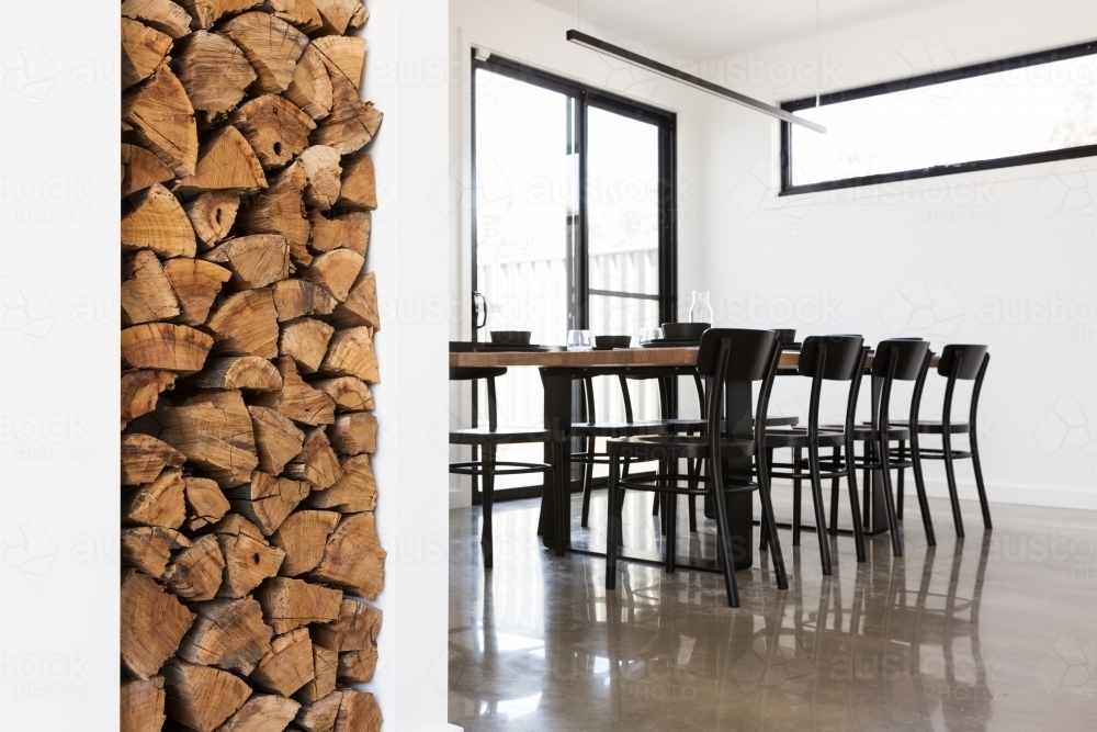 Wood stack feature in lounge with dining table in background - Australian Stock Image