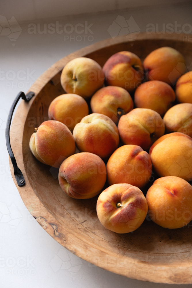 Wooden bowl in natural light full of ripe home grown peaches - Australian Stock Image