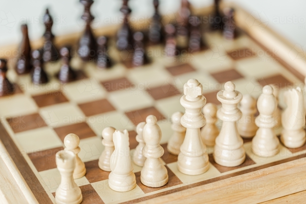 Wooden chess pieces set up on board game indoors - Australian Stock Image