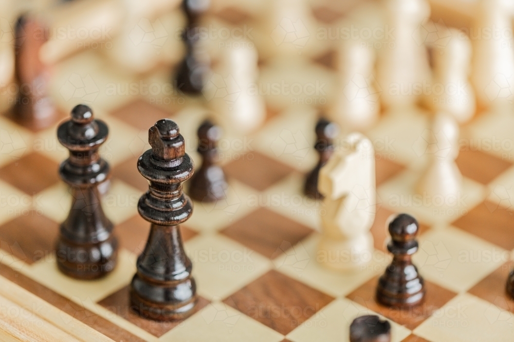 Wooden chess pieces set up on board game indoors - Australian Stock Image