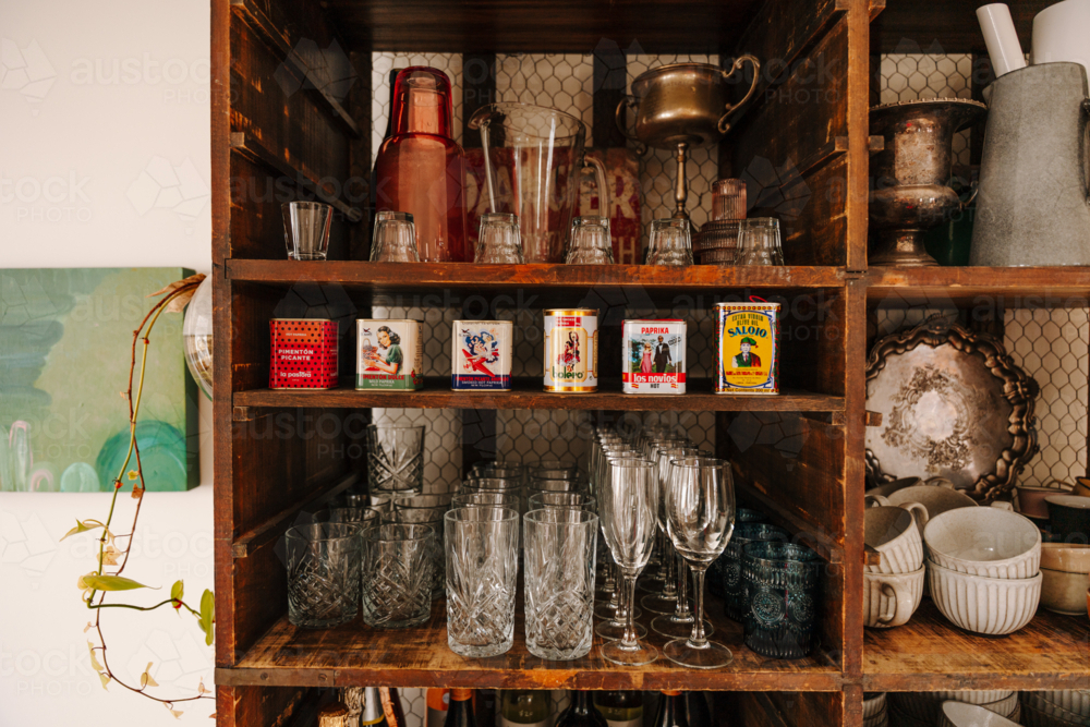 Wooden kitchen shelf displays a curated mix of vintage charm and glass wares - Australian Stock Image