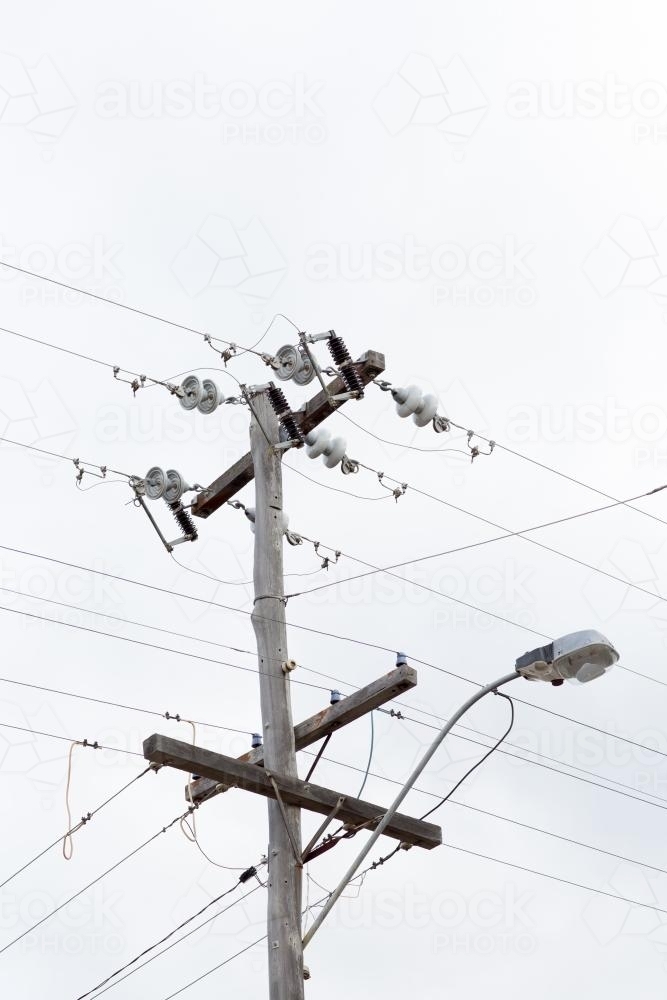 Wooden power pole with street light showing electric wires and insulators. - Australian Stock Image