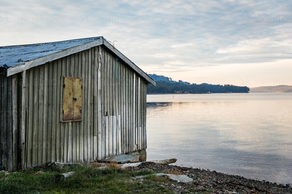 Wooden shack beside water - Australian Stock Image