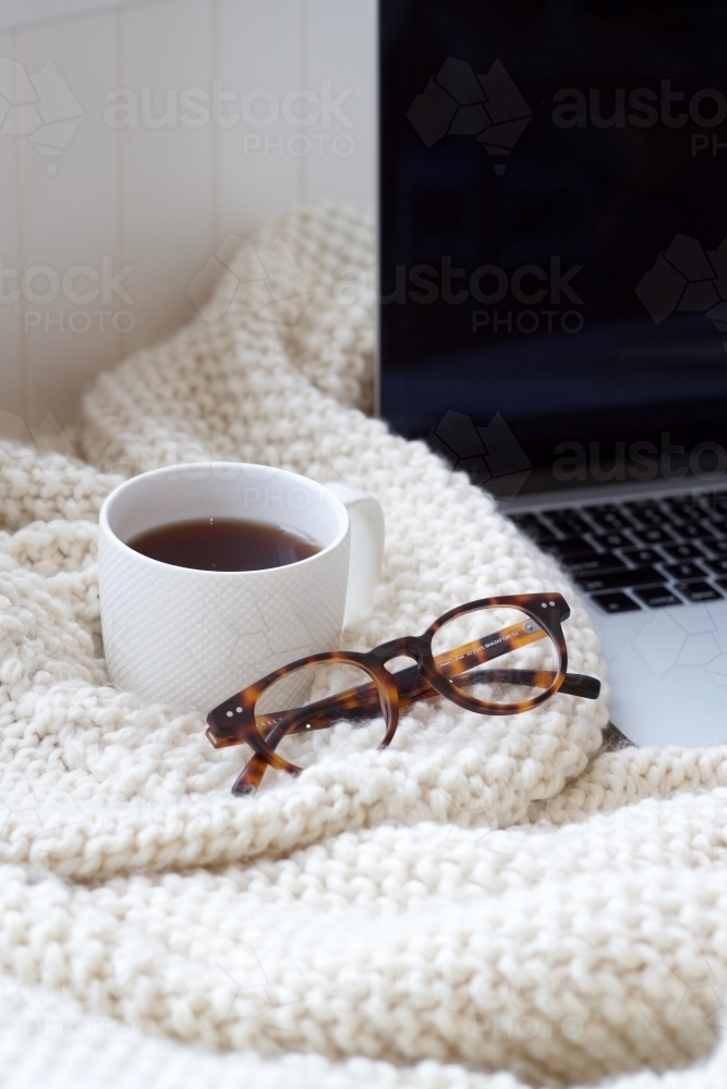 Woollen knitted blanket with coffee mug, glasses and laptop computer - Australian Stock Image