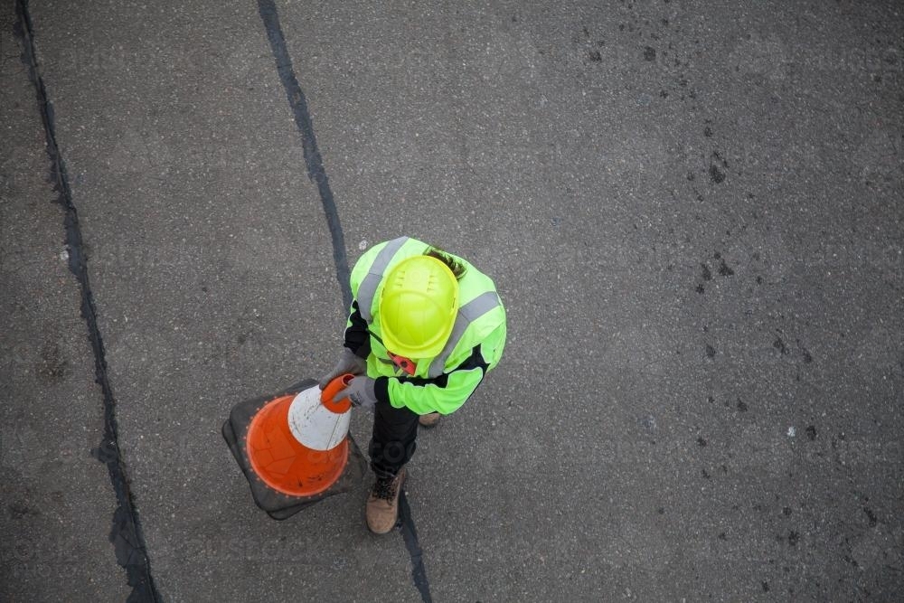 Worker in yellow reflective clothing setting out road cones - Australian Stock Image