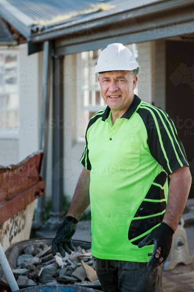 Worker on a construction site with a wheelbarrow full of rocks - Australian Stock Image