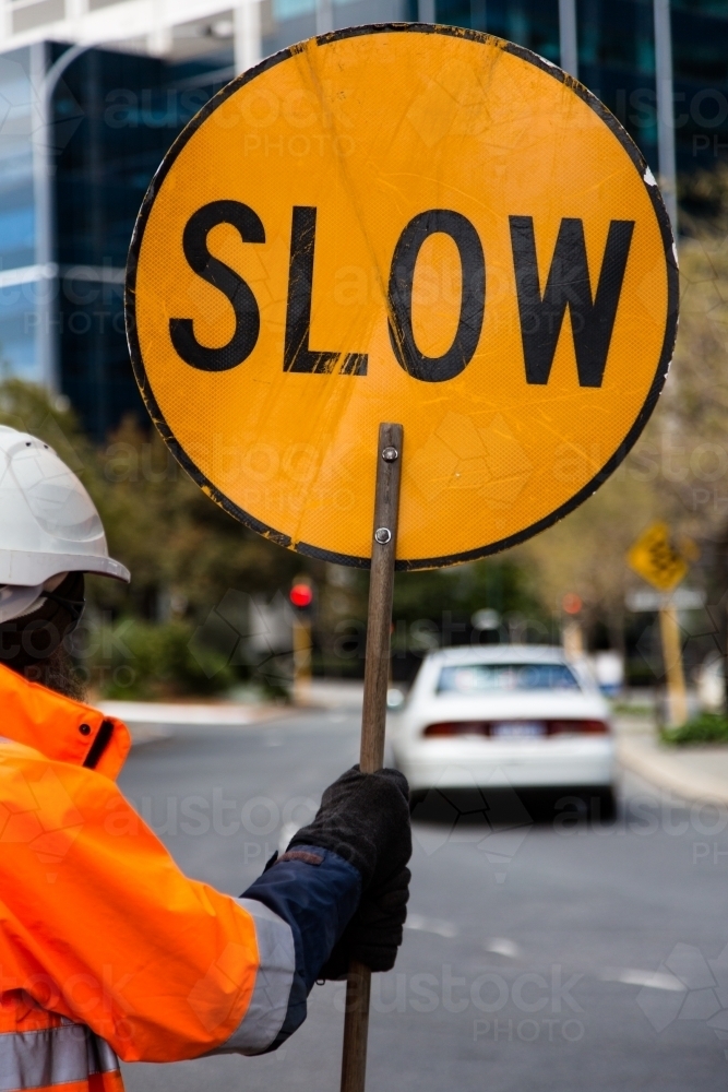 worker wearing high vis holding a slow sign - Australian Stock Image