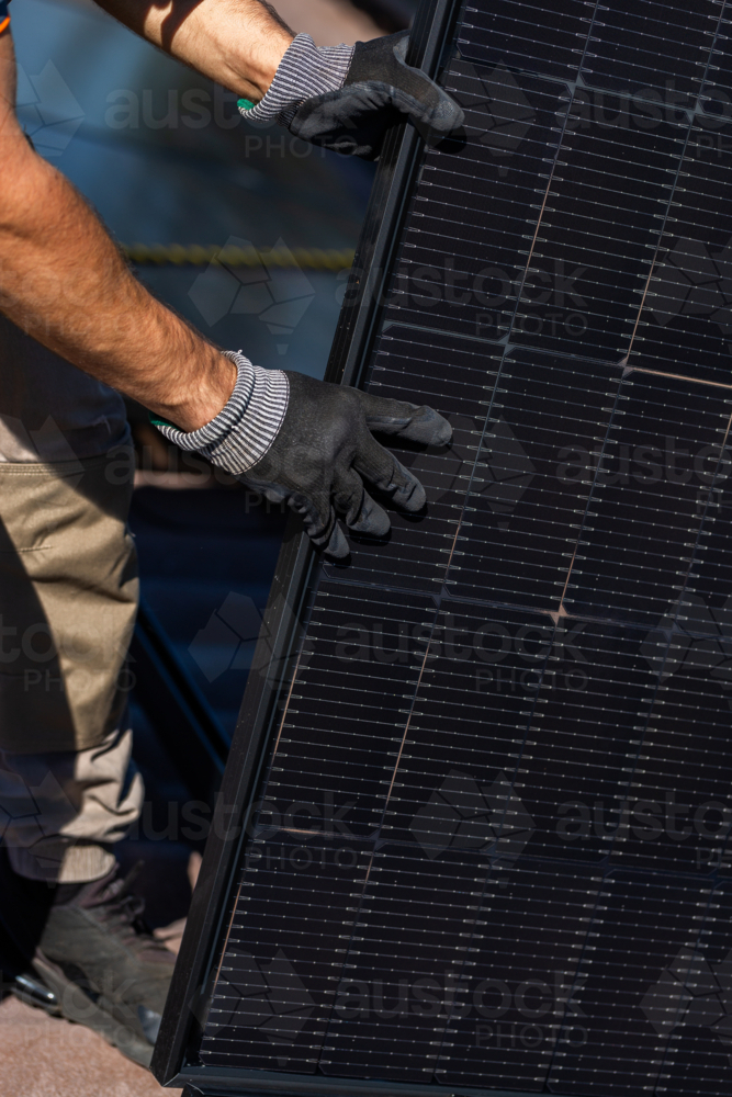 Image of Workman tradie on roof of house installing solar panel ...