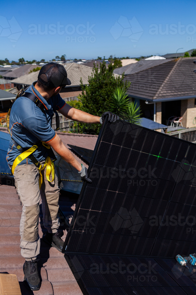 Image of Workman tradie on roof of house installing solar panel ...