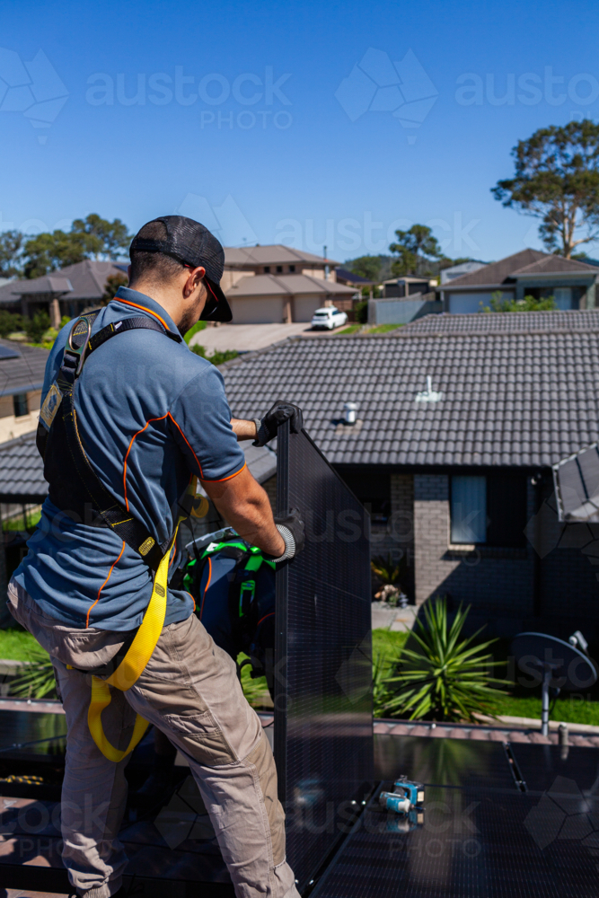 Image of Workman tradie on roof of house installing solar panel ...