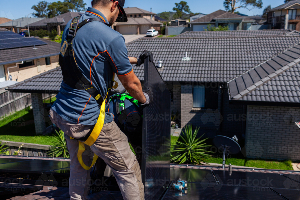Image of Workman tradie on roof of house installing solar panel ...